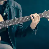 Mężczyzna w skórzanej kurtce gra na gitarze. Palce na gryfie tworzą akord, który brzmi jak początek rockowej ballady. Jaki to akord?
