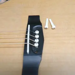 Gotowa do wymiany strun w gitarze akustycznej. Na mostku leżą nowe kołki.