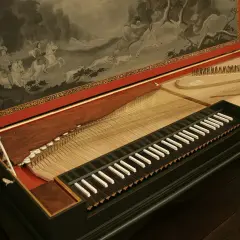 Stary klawikord z malowidłem przedstawiającym polowanie na koniach. Instrument z widocznymi strunami i klawiszami.
