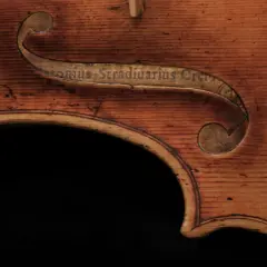 Fragment instrumentu Stradivarius z wygrawerowanym napisem. Drewno o ciepłym odcieniu, widoczne usłojenie.