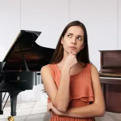 Kobieta zastanawia się, czy wybrać eleganckie pianino, czy okazały fortepian.