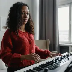 Kobieta w czerwonym swetrze gra na keyboardzie, tworząc melodię w tonacji F dur.