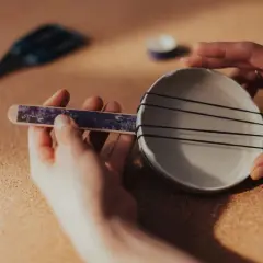Dłonie tworzą domowy instrument perkusyjny z talerzyka i gumek.