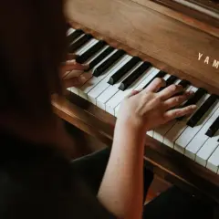 Dłonie grają na pianinie Yamaha, tworząc melodię e dur piano.