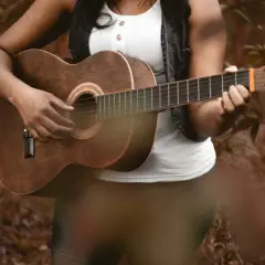 Osoba gra na gitarze akustycznej, pięknym instrumencie na gitarze, w otoczeniu natury.