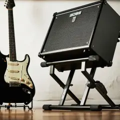 Czarna gitara elektryczna i wzmacniacz BOSS na statywie. Gotowe do wydobycia wspaniałych dźwięków na gitarze.