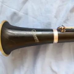 Część klarnetu z napisem "Concerto" i złotym pierścieniem. Widoczna jest budowa klarnetu, jego czarny korpus i metalowe klapy.