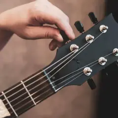 Dłoń kręci kluczem, strojąc gitarę. Słychać czysty dźwięk e, gotowy do gry.