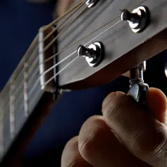 Dłoń kręci kluczem, precyzyjne **guitalele strojenie**. Idealny dźwięk tuż za rogiem.