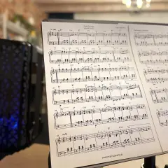 Nuty "Fale Dunaju" na stojaku, obok czarnej harmonijki z niebieskimi światłami.