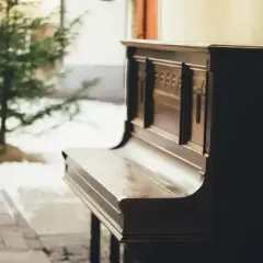 Stare pianino, gotowe do zagrania pięknych piosenek na pianino, stoi obok choinki.