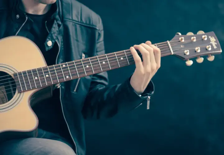 Zwinne palce gitarzysty tworzą akord na gryfie.