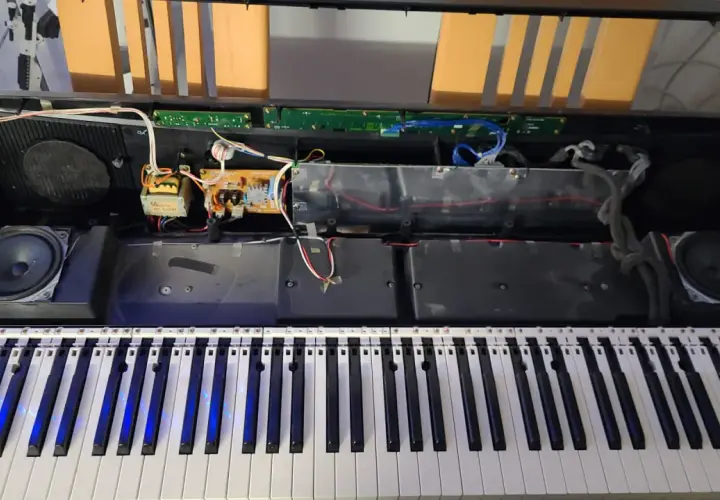 Wnętrze keyboardu Yamaha podczas naprawy. Widoczne głośniki, płytki drukowane i okablowanie.
