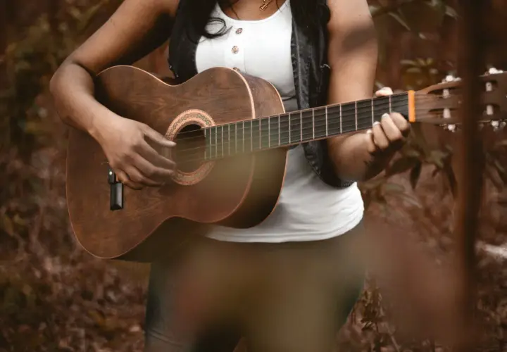 Osoba gra na gitarze akustycznej, pięknym instrumencie na gitarze, w otoczeniu natury.