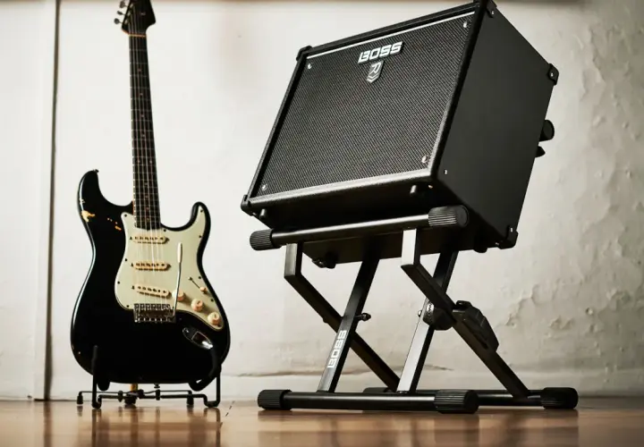 Czarna gitara elektryczna i wzmacniacz BOSS na statywie. Gotowe do wydobycia wspaniałych dźwięków na gitarze.