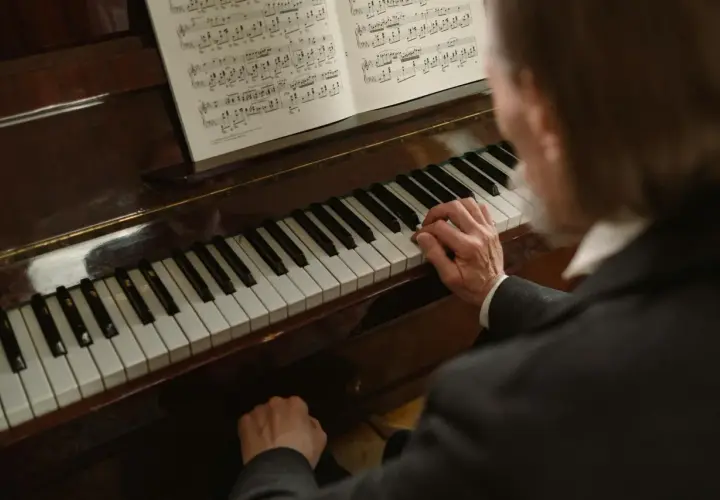 Dłonie muzyka grają melodię w tonacji **d dur** na fortepianie, nuty leżą otworem.