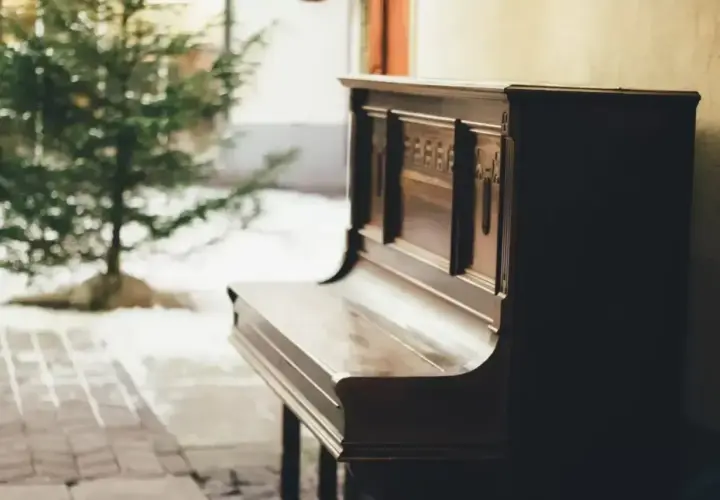 Stare pianino, gotowe do zagrania pięknych piosenek na pianino, stoi obok choinki.
