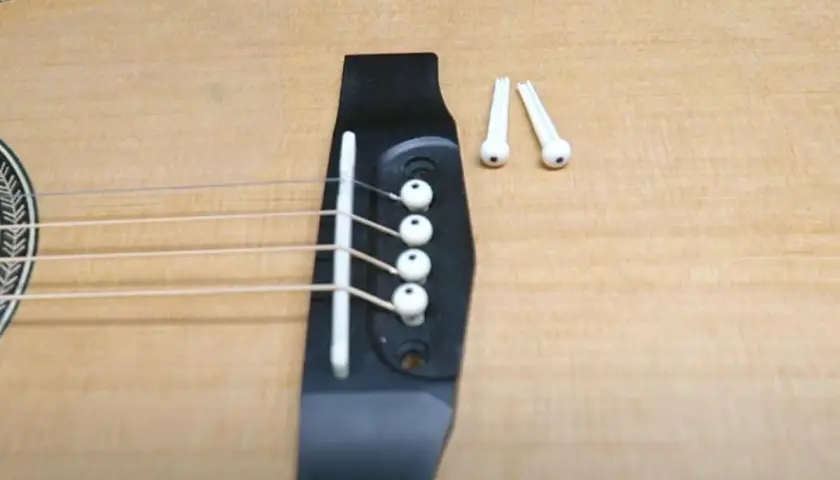 Gotowa do wymiany strun w gitarze akustycznej. Na mostku leżą nowe kołki.