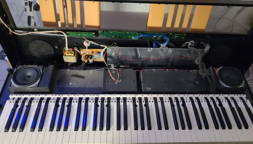 Wnętrze keyboardu Yamaha podczas naprawy. Widoczne głośniki, płytki drukowane i okablowanie.