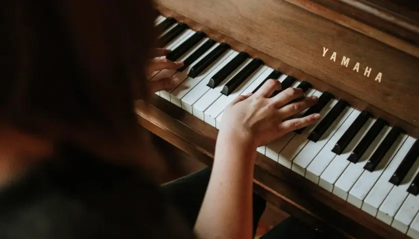 Dłonie grają na pianinie Yamaha, tworząc melodię e dur piano.