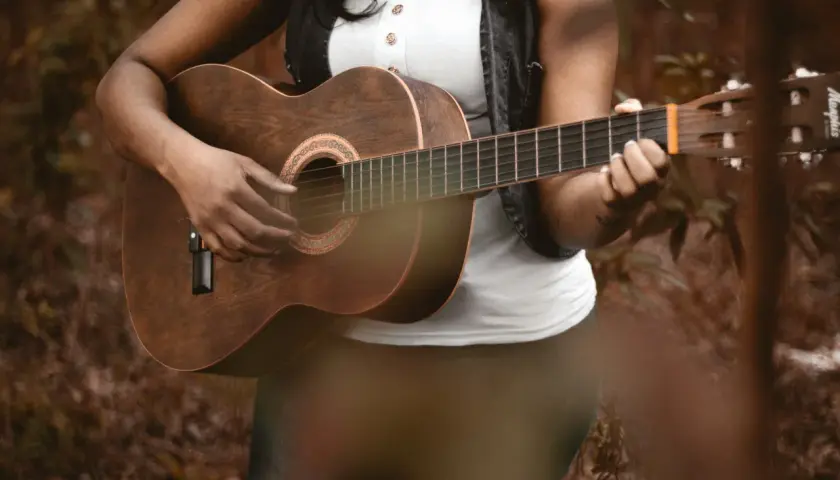 Osoba gra na gitarze akustycznej, pięknym instrumencie na gitarze, w otoczeniu natury.