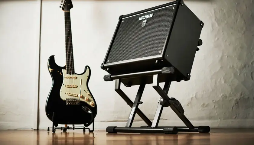 Czarna gitara elektryczna i wzmacniacz BOSS na statywie. Gotowe do wydobycia wspaniałych dźwięków na gitarze.