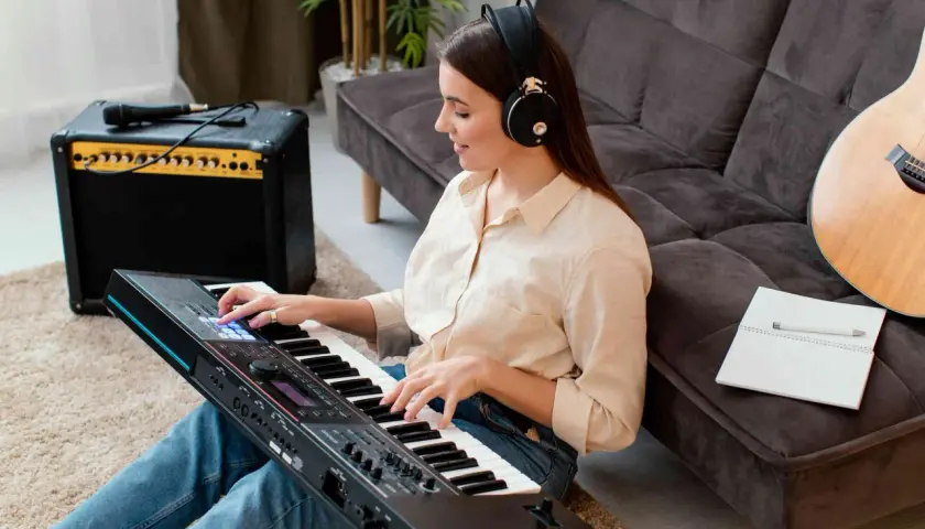 Kobieta w słuchawkach gra na keyboardzie japońskiej marki. Obok stoi wzmacniacz i gitara.