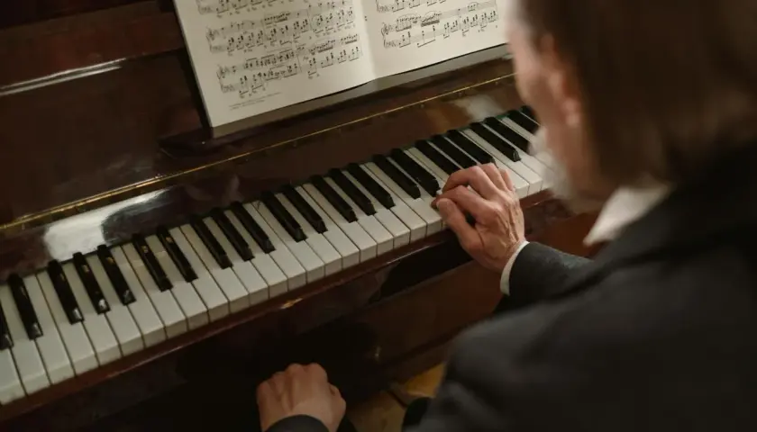 Dłonie muzyka grają melodię w tonacji **d dur** na fortepianie, nuty leżą otworem.