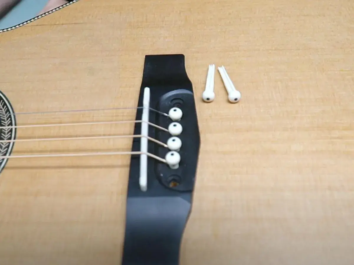Gotowa do wymiany strun w gitarze akustycznej. Na mostku leżą nowe kołki.