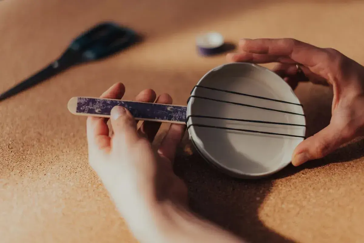Dłonie tworzą domowy instrument perkusyjny z talerzyka i gumek.