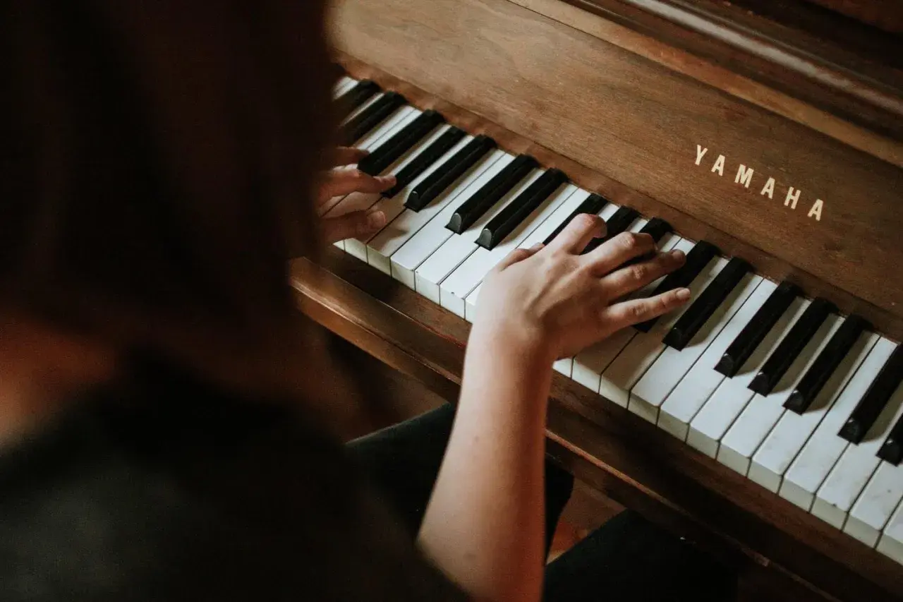 Dłonie grają na pianinie Yamaha, tworząc melodię e dur piano.