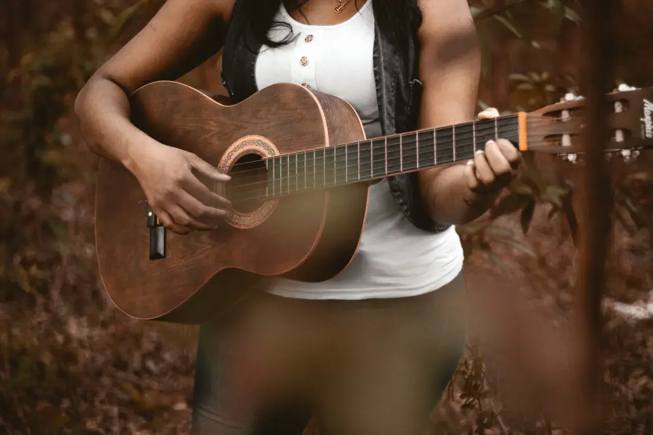 Osoba gra na gitarze akustycznej, pięknym instrumencie na gitarze, w otoczeniu natury.