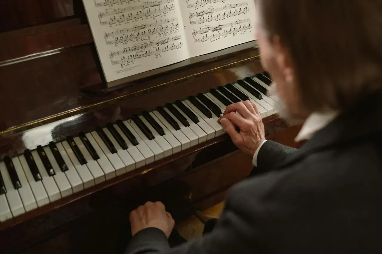Dłonie muzyka grają melodię w tonacji **d dur** na fortepianie, nuty leżą otworem.