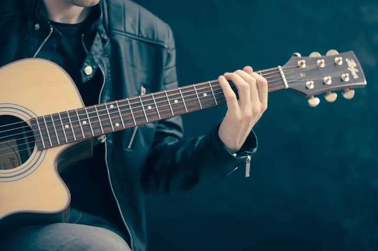 Mężczyzna w skórzanej kurtce gra na gitarze. Palce na gryfie tworzą akord, który brzmi jak początek rockowej ballady. Jaki to akord?