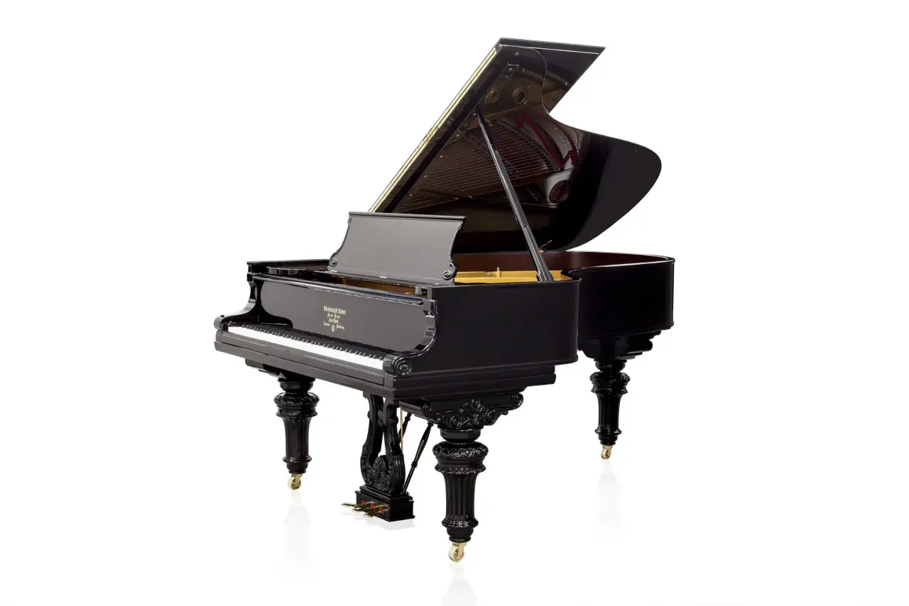 Czarny, błyszczący fortepian z otwartą klapą, prezentujący swoje wnętrze. To instrument, który zachwyca elegancją, w przeciwieństwie do mniejszego pianina.