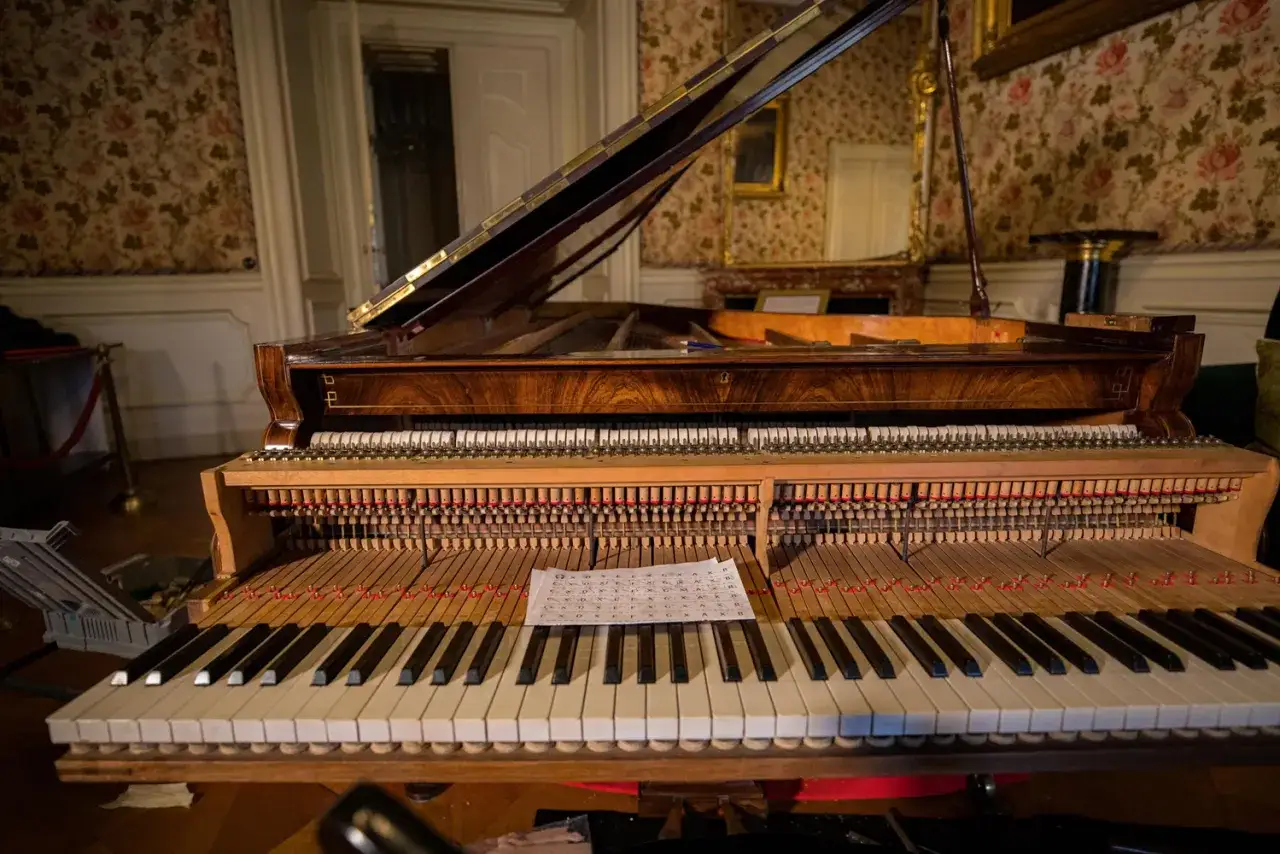 Widok wnętrza zabytkowego pianina, być może tego, na którym grał Chopin. Nuty leżą na klawiaturze.